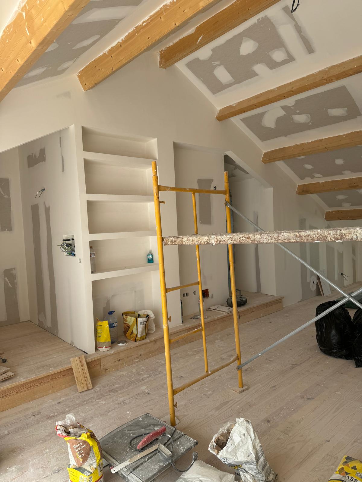 Obra real Multigesso — teto falso inclinado em pladur com vigas de madeira e estantes em gesso cartonado